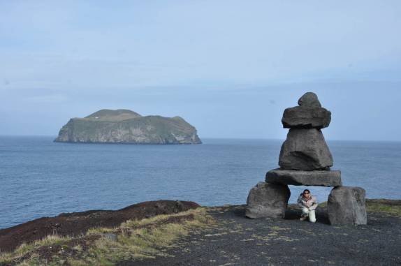 Arriscando-se sob monumento na ilha de Heimaey, no sul da Islândia